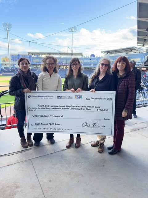 Five PACE award recipients holding a large donation check