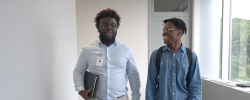 Two students in blue button down shirts walking down a hallway
