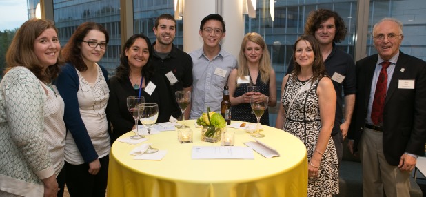A group of people standing in front of a round table and posing for the camera.