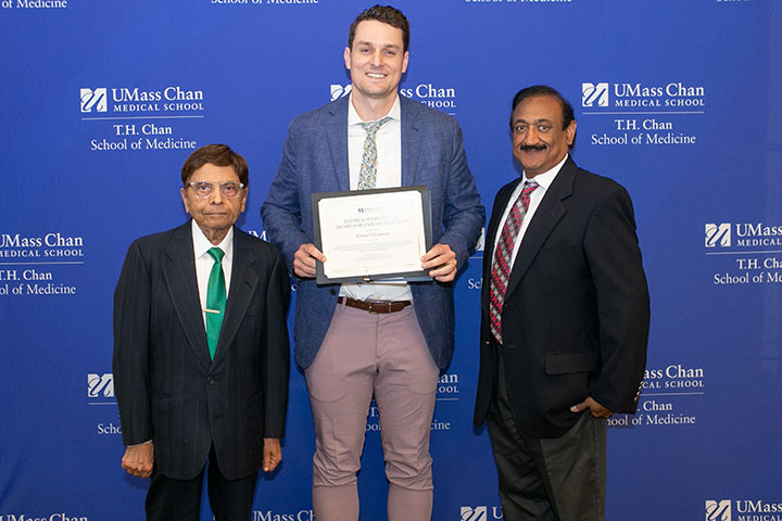 Kevin O'Connor holding a plaque alongside Satish Gupta and his son, Sanjeev.