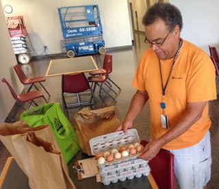 The image shows a man in an orange shirt opening a carton of eggs