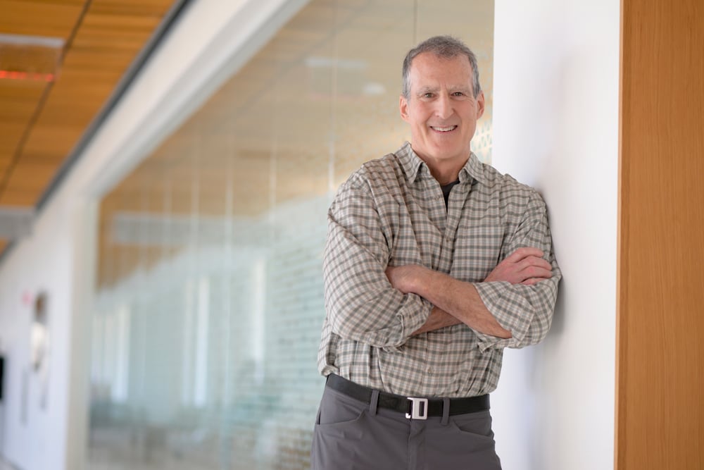 Photo of Craig Mello leaning against a wall in the Paul J. DiMare Center. 