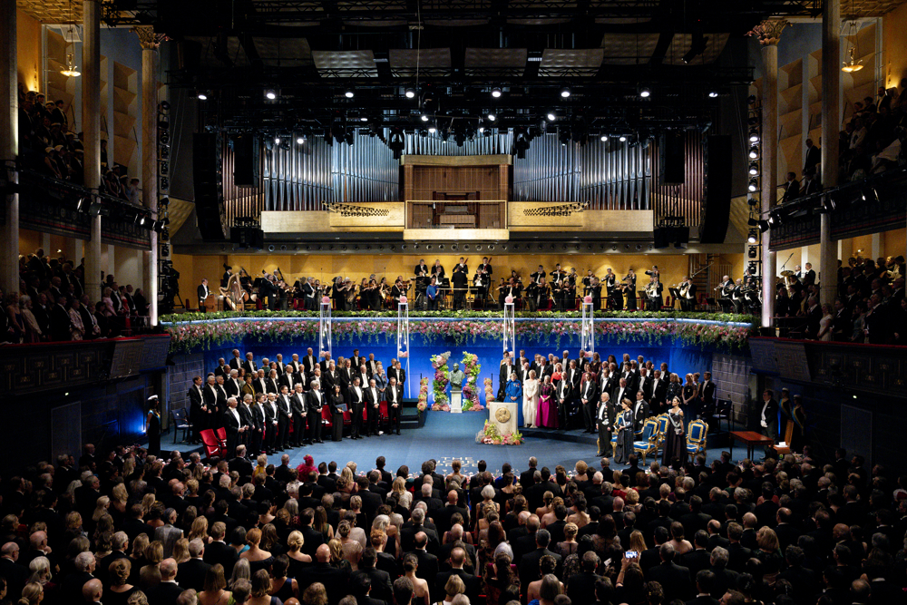 A crowd in front of the honorees on stage with an orchestra just above