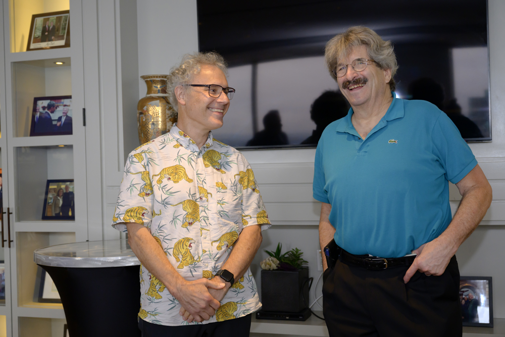 Dr. Ambros and Dr. Ruvkun standing side-by-side at the UMass Club in Boston the afternoon of the Nobel announcement. Ambros is wearing a shirt with yellow tigers. Gary wears a turquoise polo shirt. 
