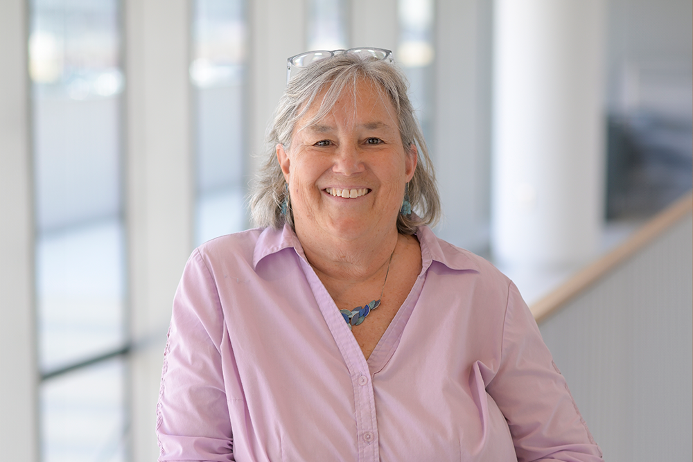 Photo of Melissa Moore smiling and leaning on a stair rail in the Paul J. DiMare Center.
