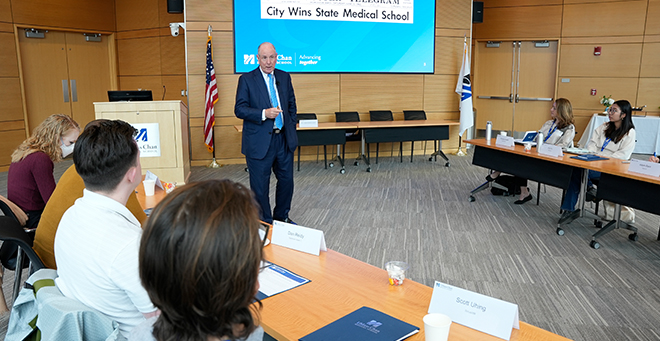 The chancellor wearing a suit stands in front of media fellows