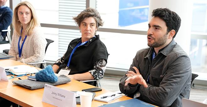 Journalists sitting side by side at a table engaging in a discussion