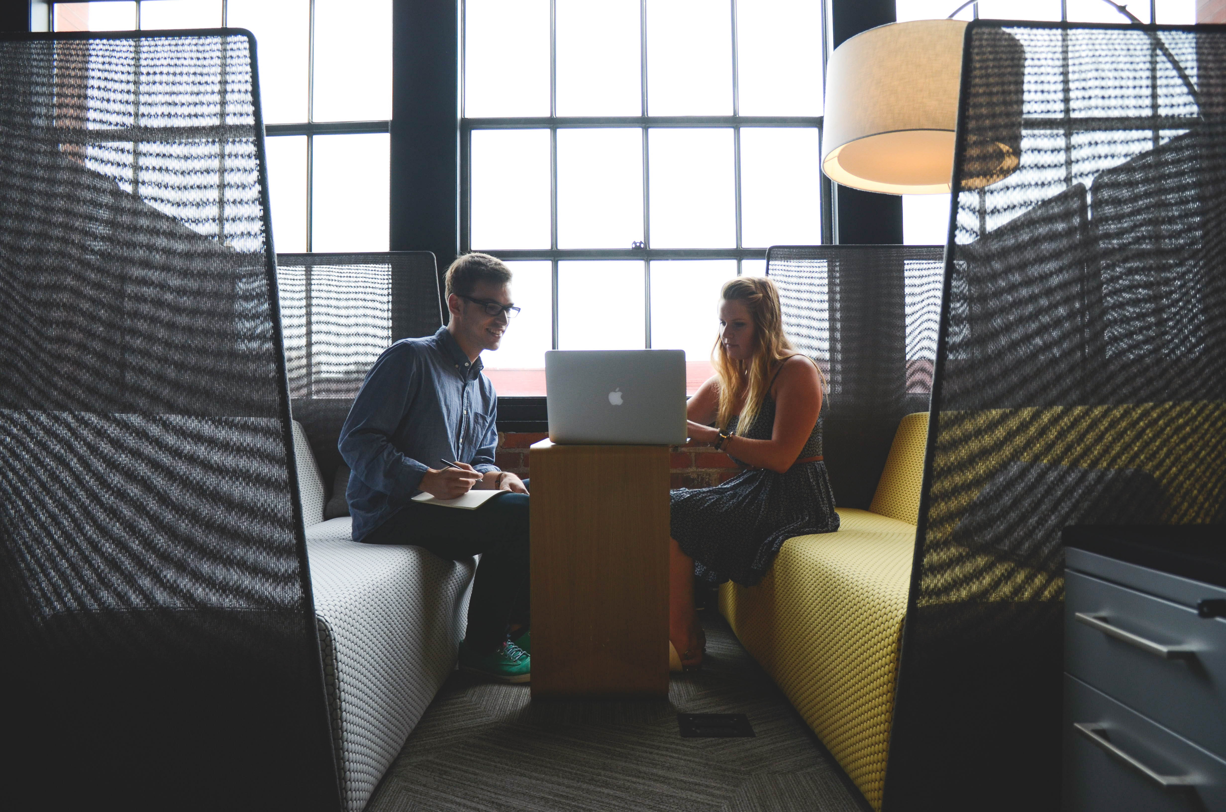 Two people sitting at a table with a laptop