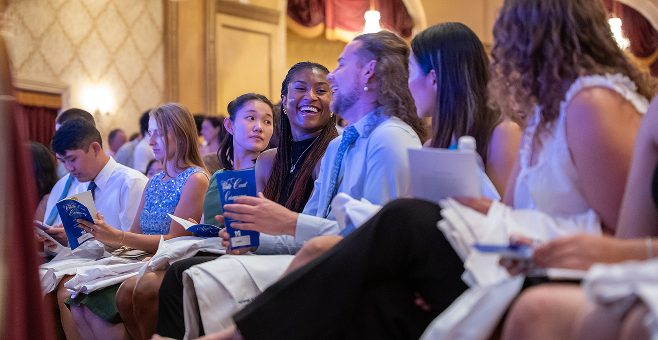 Students share a laugh at the start of the White Coat Ceremony for the T.H. Chan School of Medicine Class of 2029.